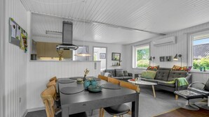 Un intérieur moderne avec un coin repas, un canapé et une cuisine en arrière-plan.
