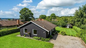 Une maison moderne à l’extérieur sombre, dotée d’un toit en pente et d’une pelouse bien entretenue.