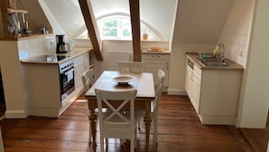 A kitchen with a wooden table and chairs, a stove, and a sink.