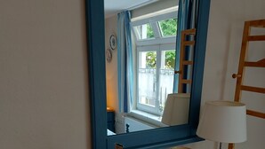 A room with a wooden dresser, a mirror, a vase, and a lamp. - Fewo ivy - House Gundelrebe (Bergen auf Rügen)