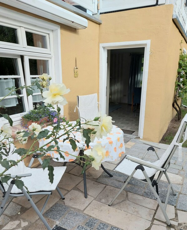 Eine Terrassengruppe mit Esstisch, umgeben von Stühlen und einem Blumentopf mit Blumen.