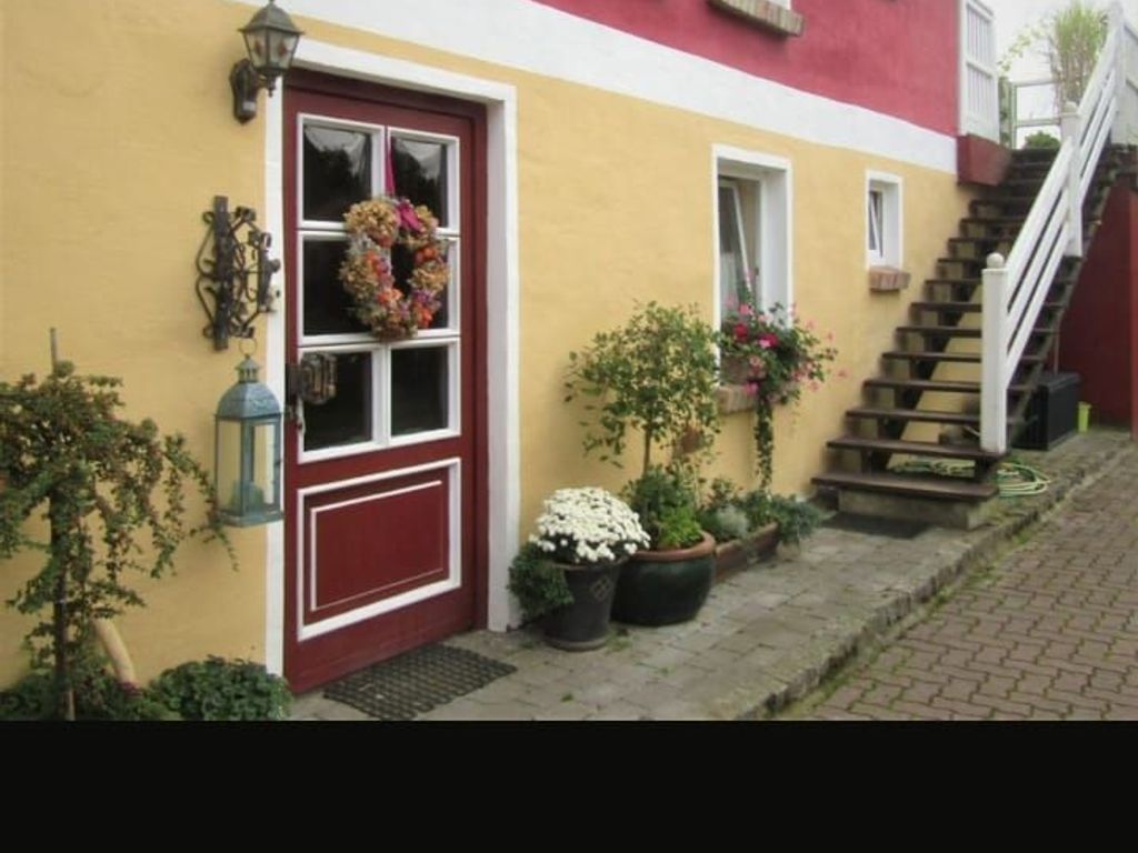 A house with a red door, a small staircase, and potted plants.