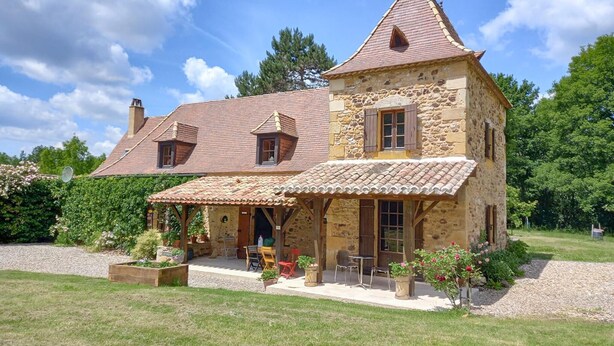 A stone house with a tiled roof, a covered porch, and a garden with potted plants and outdoor furniture. - Beautiful home in Monpazier (Monpazier)