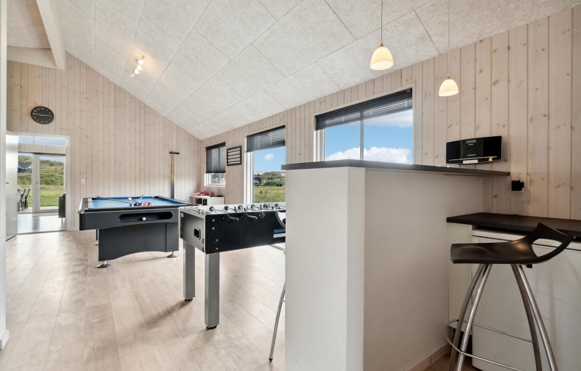 Espaço interior moderno com mesa de bilhar, mesa de futebol e bar.