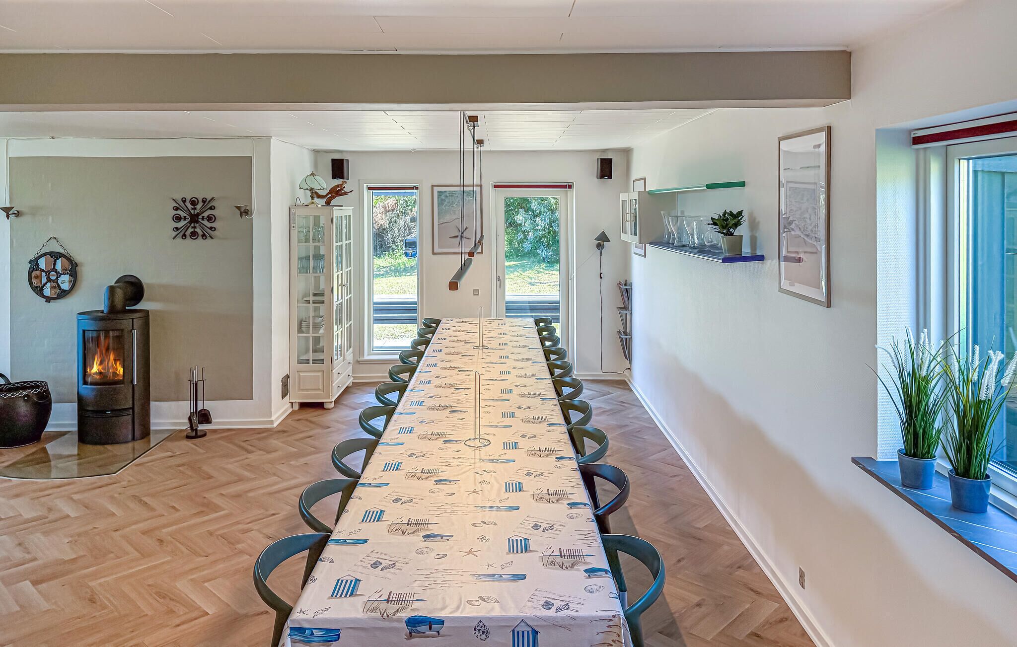A long dining table with chairs, a fireplace, and a view of the outdoors.