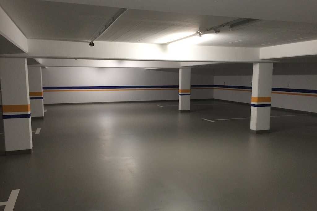 A multi-level parking garage with white pillars and blue and orange stripes.