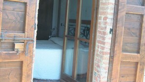 Une porte en bois avec un panneau de verre qui donne sur une pièce contenant un lit et un tapis.