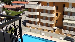 A multi-story building with balconies, a swimming pool, and a clear view of the sea. - Holiday apartment near the beach (Porto Santa Margherita)