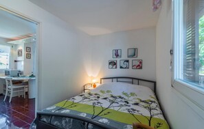Ein Schlafzimmer mit einem Bett, einem Schreibtisch und Stühlen. An den Wänden hängen gerahmte Bilder.