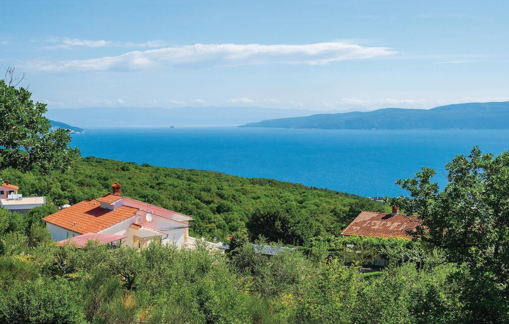 A coastal view with a house surrounded by greenery and a clear blue sea.