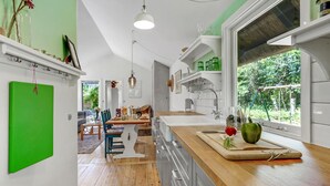 Una cucina moderna con piani di lavoro in legno, forno integrato e un'ampia finestra con vista sul verde.