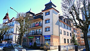 A multi-story hotel with balconies, a sign for a tour, and a gated entrance. - Zeromski (ZE05) - ZE05 (Swinoujscie)