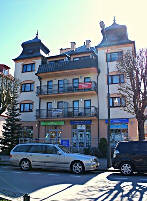 A multi-story building with balconies, a sign for a restaurant, and a car parked in front.