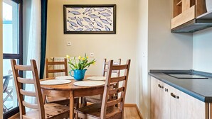 A dining area with a wooden table and chairs, a blue vase with flowers, and a fish-themed artwork on the wall. - Zeromski (ZE05) - ZE05 (Swinoujscie)