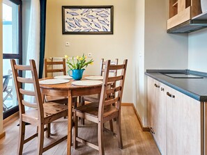 A dining area with a wooden table and chairs, a blue vase with flowers, and a fish-themed artwork on the wall. - Zeromski (ZE05) - ZE05 (Swinoujscie)