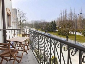 A balcony with a metal railing, a table, and chairs.