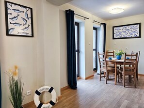 A dining area with a wooden table and chairs, a life preserver on the floor, and two framed fish illustrations on the walls.