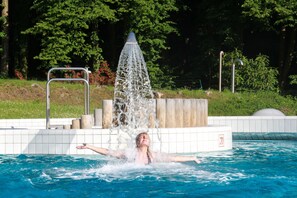 A person in a swimming pool with a water fountain feature.