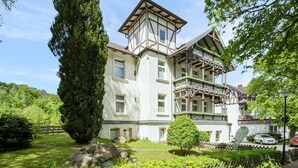 Un bâtiment traditionnel doté d’une tour imposante, de grandes fenêtres et d’un balcon orné de balustrades décoratives.