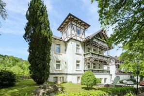 A traditional building with a prominent tower, large windows, and a balcony with ornate railings. - Single Room - Hotel Winterberg (Bad Harzburg)