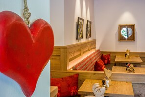Een gezellig interieur met houten meubels, een hartvormige decoratie en kunstwerken in lijsten aan de muren.