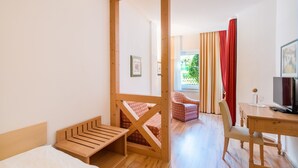 Une chambre avec un lit, un bureau, une chaise et un téléviseur.
