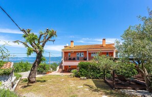 A two-story house with a balcony, surrounded by trees and a clear sky. - Cozy home in Risika with WiFi (Risika)
