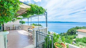A balcony with a view of the sea, a table with chairs, and a potted plant. - Nice apartment in Omis with WiFi (Omis)