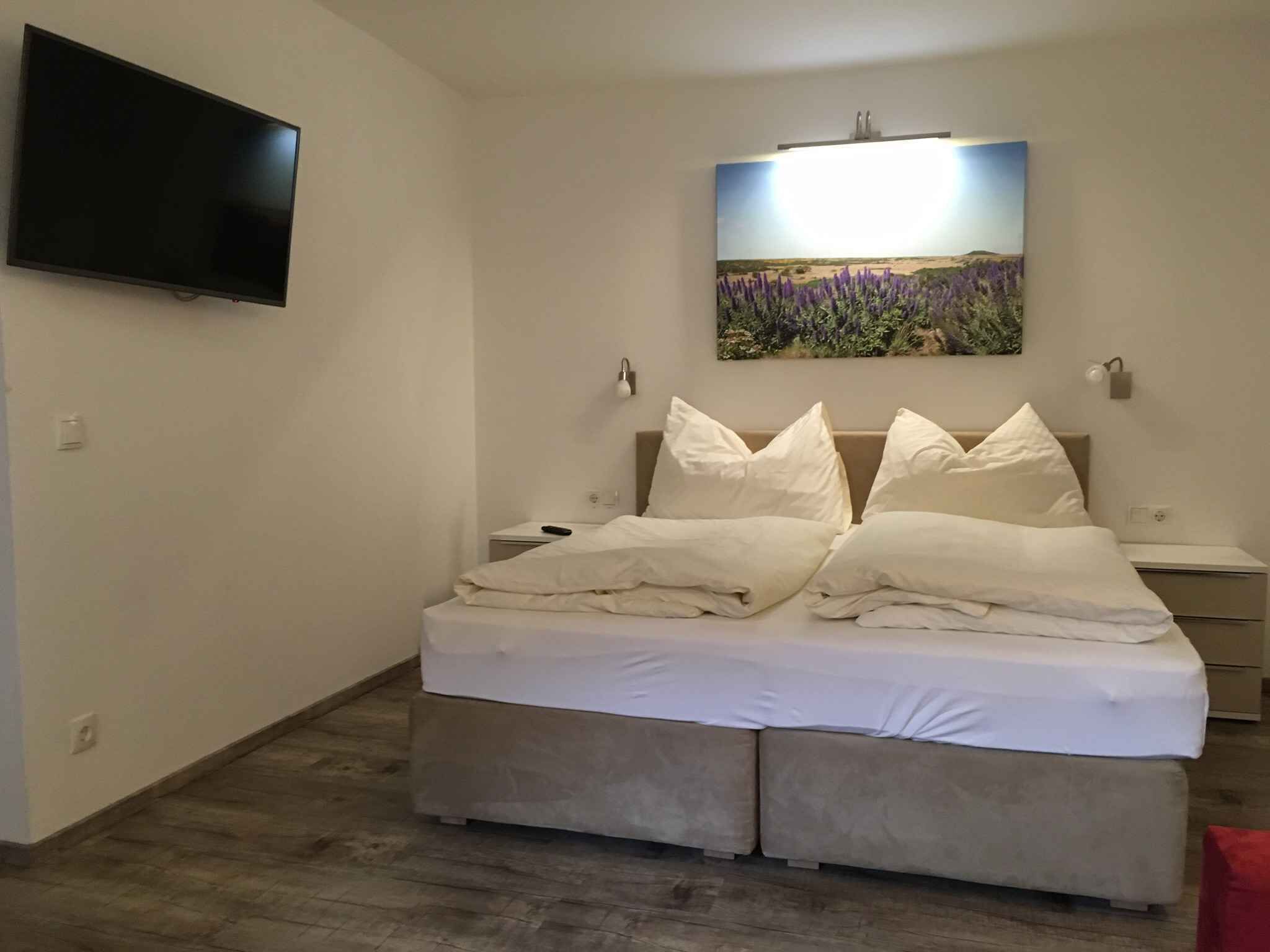 Ein Schlafzimmer mit einem Bett, einem flachbildfernseher an der Wand und einem Bild über dem Bett.