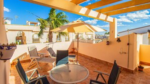 A rooftop terrace with a round glass table, four chairs, and a large umbrella. - 2 bedroom beautiful home in La Florida (La Florida)