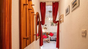 A hallway with wooden doors, red curtains, a grey sofa with red cushions, and framed pictures on the wall. - 2 bedroom beautiful home in La Florida (La Florida)