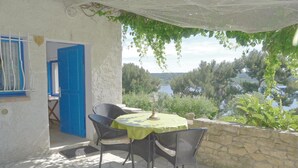 A patio with a table and chairs, a view of a lake, and a stone wall. - Stunning apartment in ISTRES with WiFi (ISTRES)