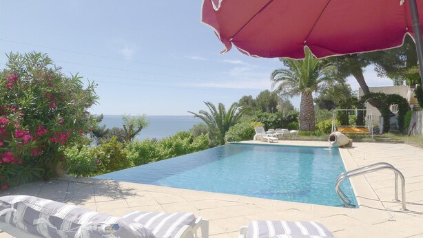 A pool with lounge chairs and an umbrella, surrounded by greenery and a view of the sea. - Stunning apartment in ISTRES with WiFi (ISTRES)