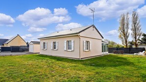 Ein eingeschossiges Haus mit Satteldach, umzäunter Garten und Picknicktisch.
