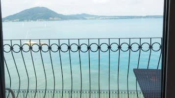 Een balkon met uitzicht op een kalm wateroppervlak, een verre berg en een heldere lucht.