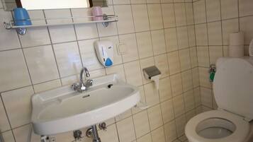 Een badkamer met een wastafel, toilet en een plank met toiletartikelen.