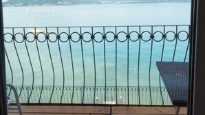 Un balcón con vista a un cuerpo de agua tranquilo, una montaña distante y un cielo despejado.