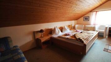 A bedroom with a wooden ceiling, a bed, a chair, and a small table.