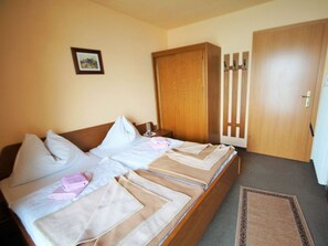 Ein Doppelbett mit zwei Kissen, ein Nachttisch, ein Holzschrank und eine Tür mit Griff.