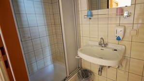 A bathroom with a shower, sink, and a mirror.