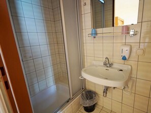 Ein Badezimmer mit Dusche, Waschbecken und Spiegel.