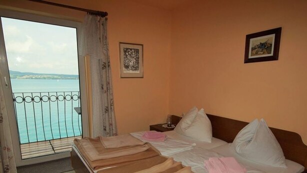 A double bed with a view of the sea through a balcony.