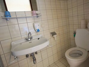 Ein Badezimmer mit Waschbecken, Toilette und Ablage für Toilettenartikel.