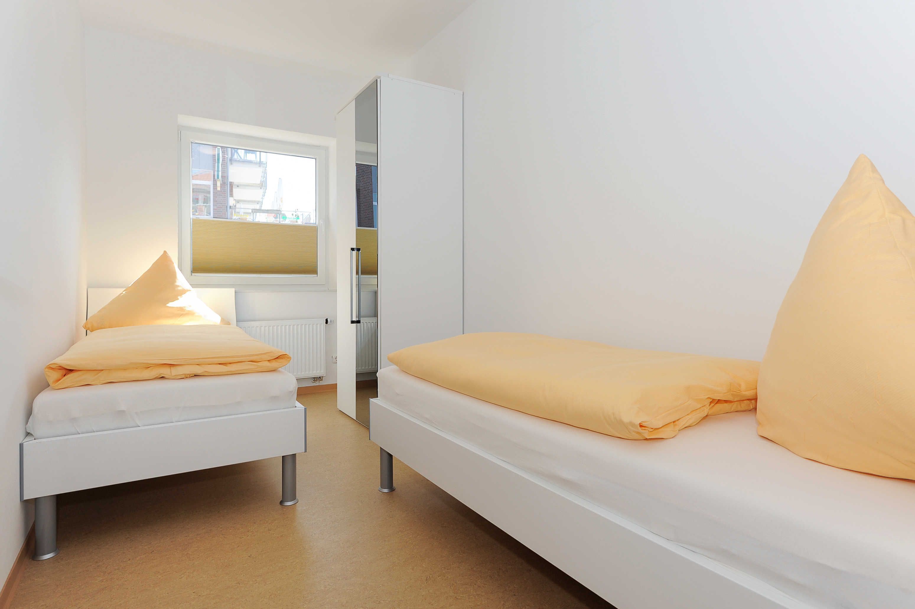 Un dormitorio con cama, mesita de noche y ventana.