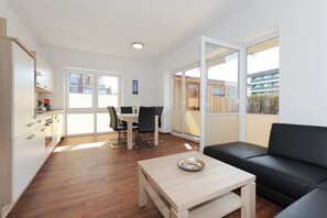Um apartamento moderno com cozinha, sala de jantar e varanda com vista para prédios.