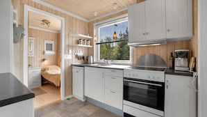 Een moderne keuken met witte kastjes, een ingebouwde oven en een raam met uitzicht op groen.