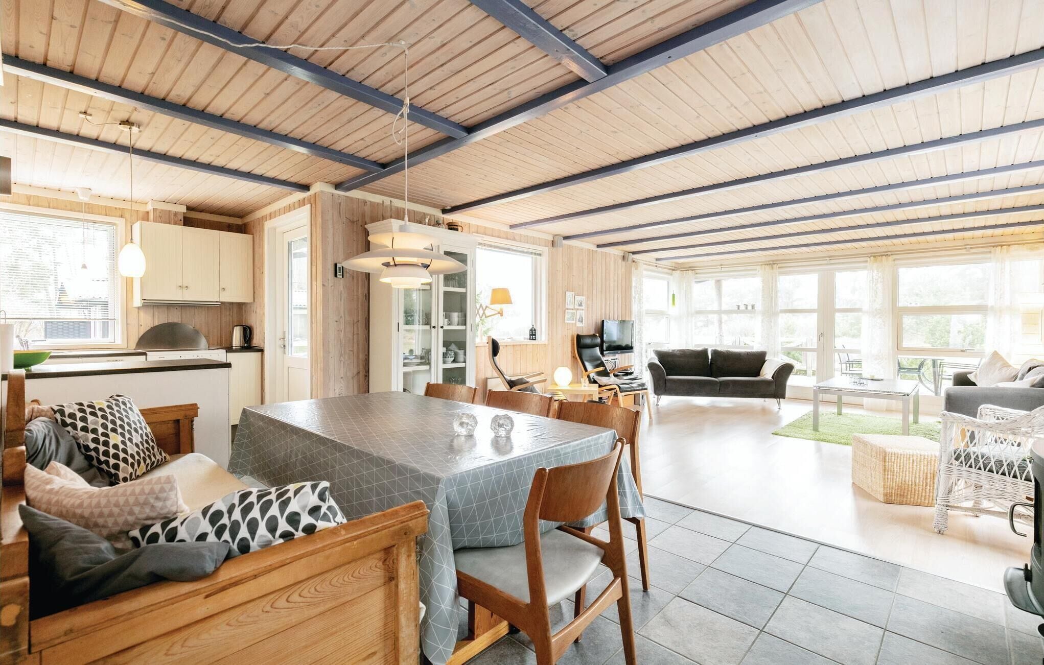 A spacious living area with a large dining table, wooden furniture, and a view of the outdoors.