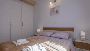 A bedroom with a bed, two bedside tables with lamps, a nightstand, a wardrobe, and a framed picture on the wall.