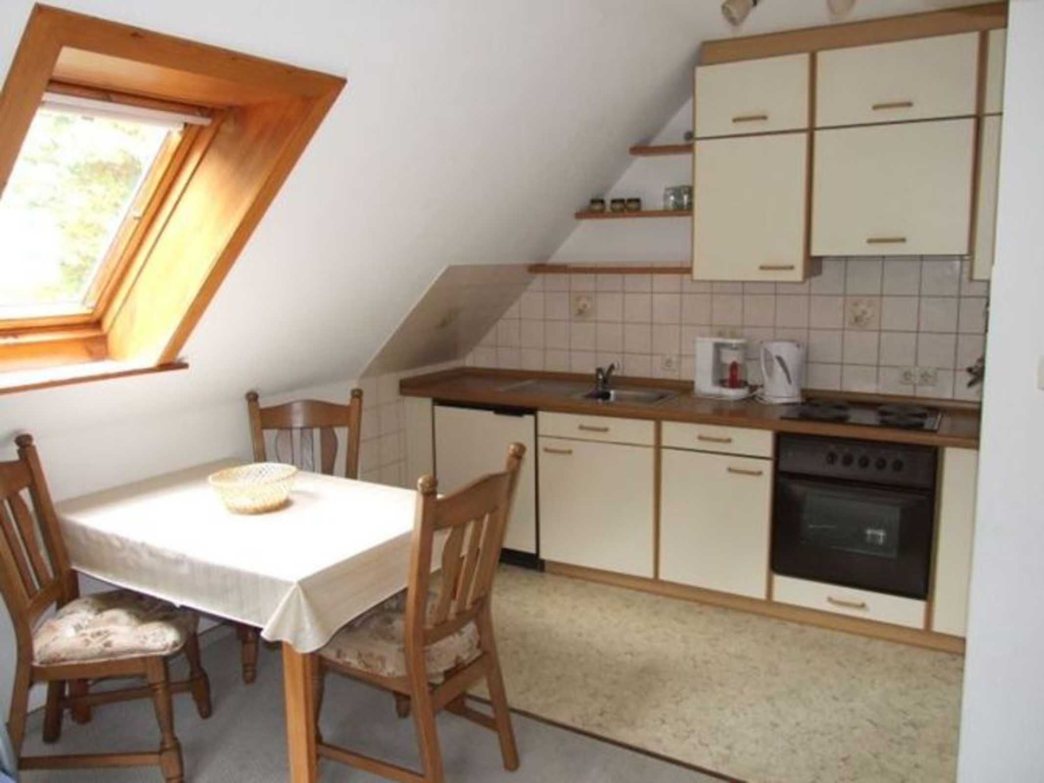 A small kitchen with a dining table, chairs, a window, and a stove.