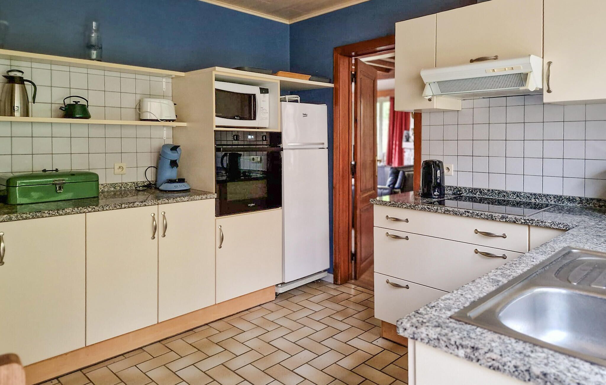 A kitchen with white cabinets, a microwave, a kettle, and a coffee maker on the countertop.